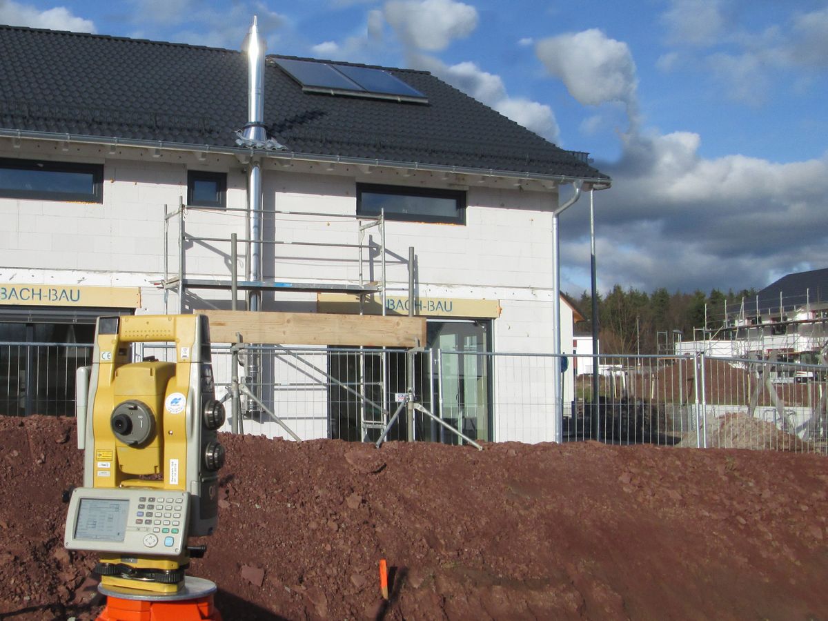 Tachymeter vor einem neuen Wohnhaus bei der Gebäudeaufnahme